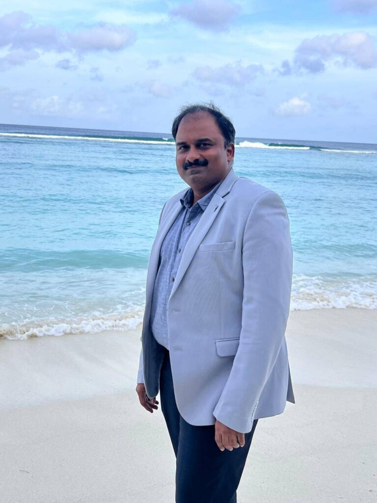 Arul Subramaniam standing in front of the sea