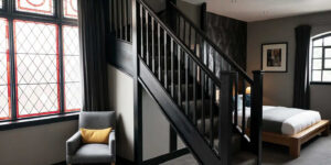 A hotel room with a bed and staircase leading to the second floor.