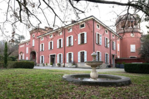A large Italian villa behind a fountain.