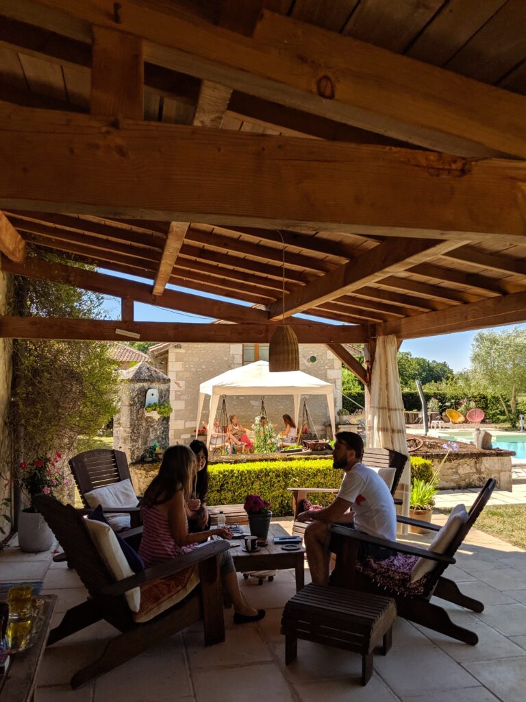 People sitting around a table on a patio on a summer's day.