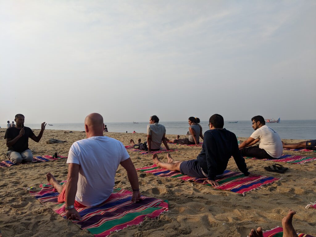 People doing yoga on a beach.