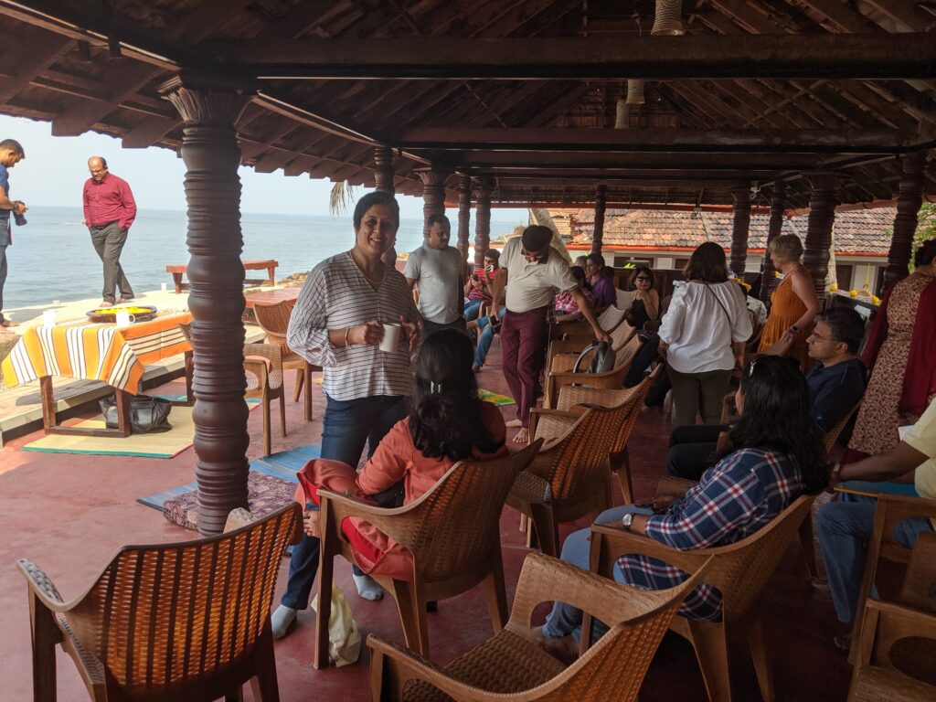 A group of people sitting in a veranda on a beach in India waiting for a presentation to begin.