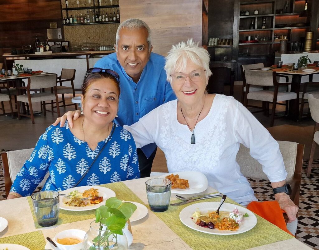 Ramesh and Tulsi Prasad with Sue Knight sitting at a table.
